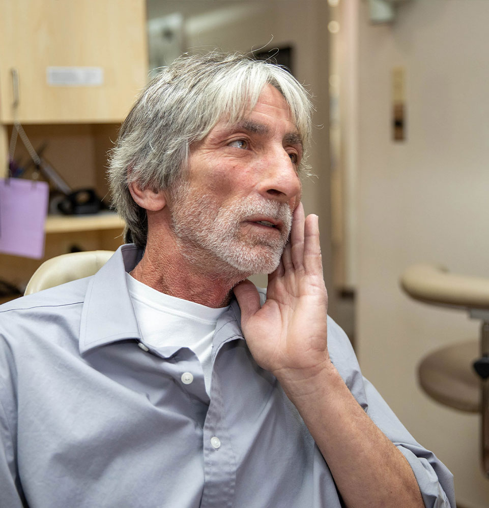 dental patient gesturing at mouth for pain