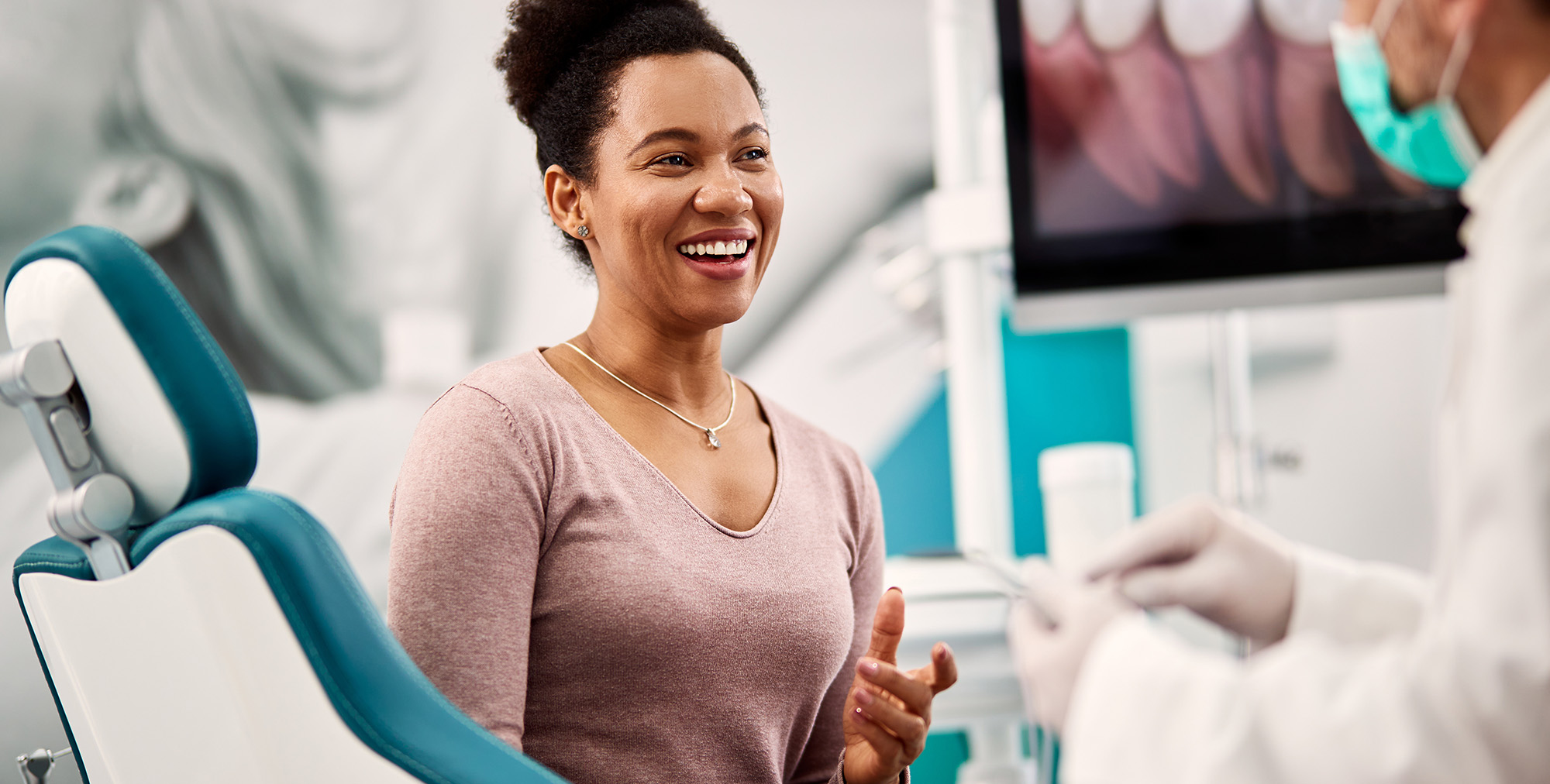 Happy woman talks to her dentist during appointment at dental clinic.